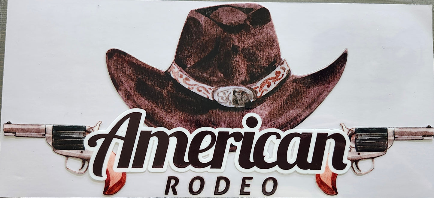 A die-cut sticker featuring a brown cowboy hat with a silver band, two silver revolvers, and the words 'American RODEO' in stylized script and block lettering on a white background.